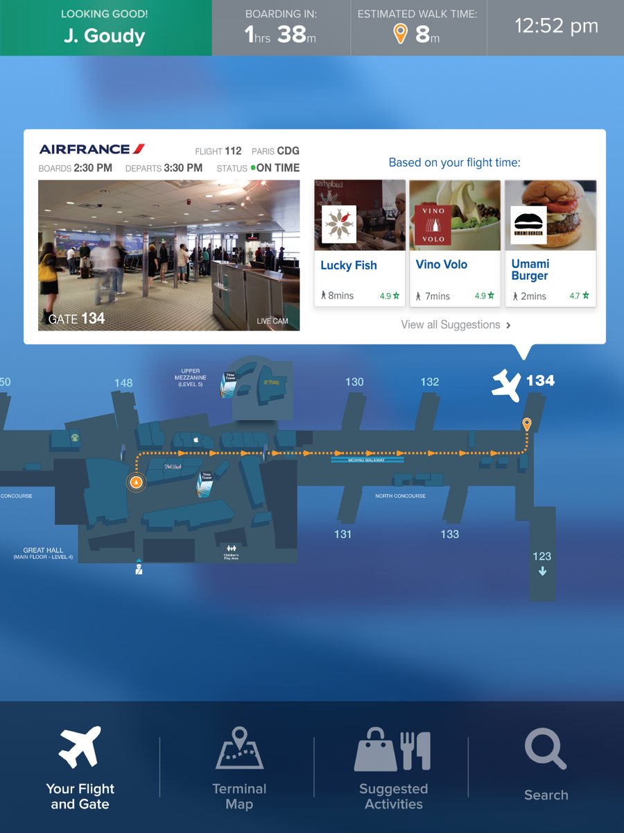 A kiosk screen for the traveler’s Air France flight to Paris: gate 134 with a live camera, on time, the walking route on the map, and three restaurants suggested for the time available.